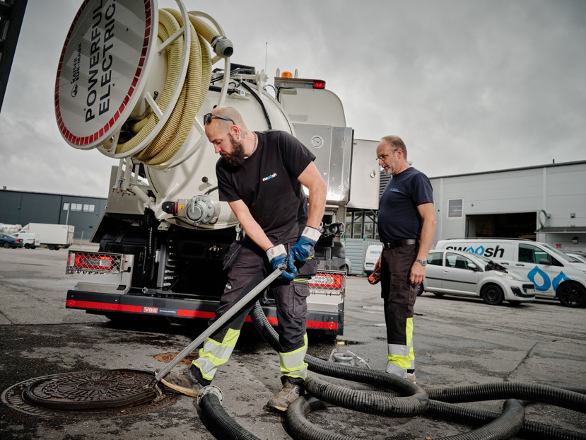 brunn spolbil slangar två män